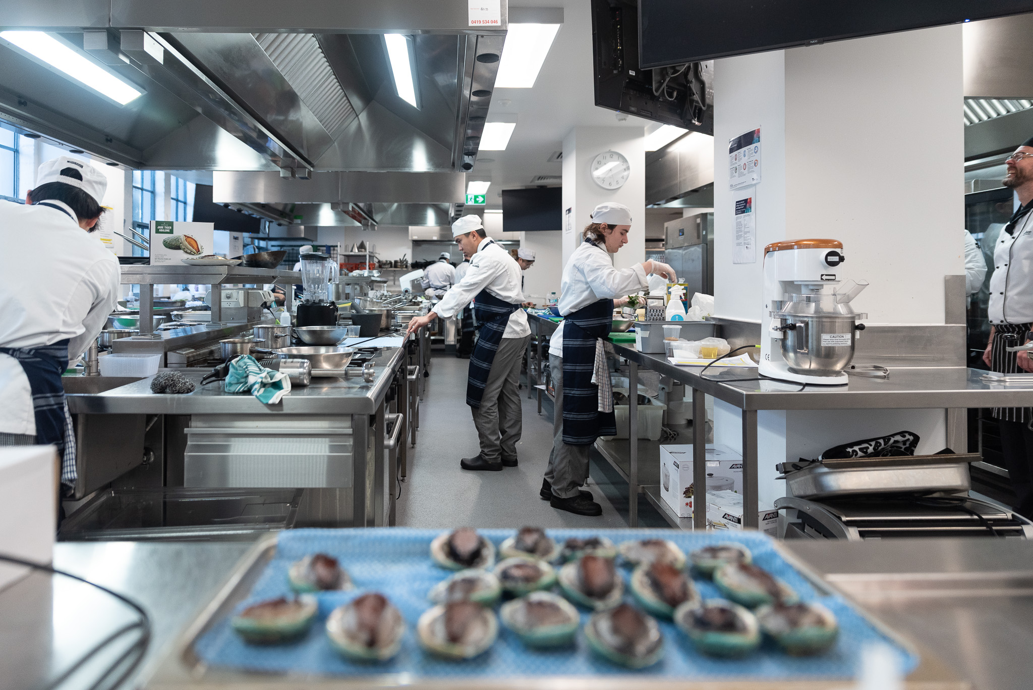 Image of a working commercial kitchen with several trainee chefs.