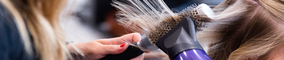 Hair being styled using a round brush and hair dryer.