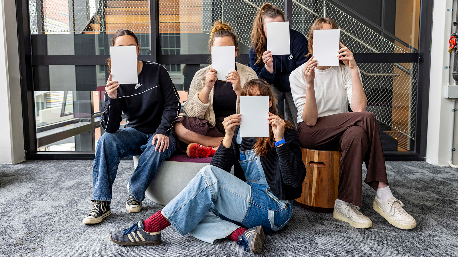 Image of young students covering their faces with white card to represent the incognito art show