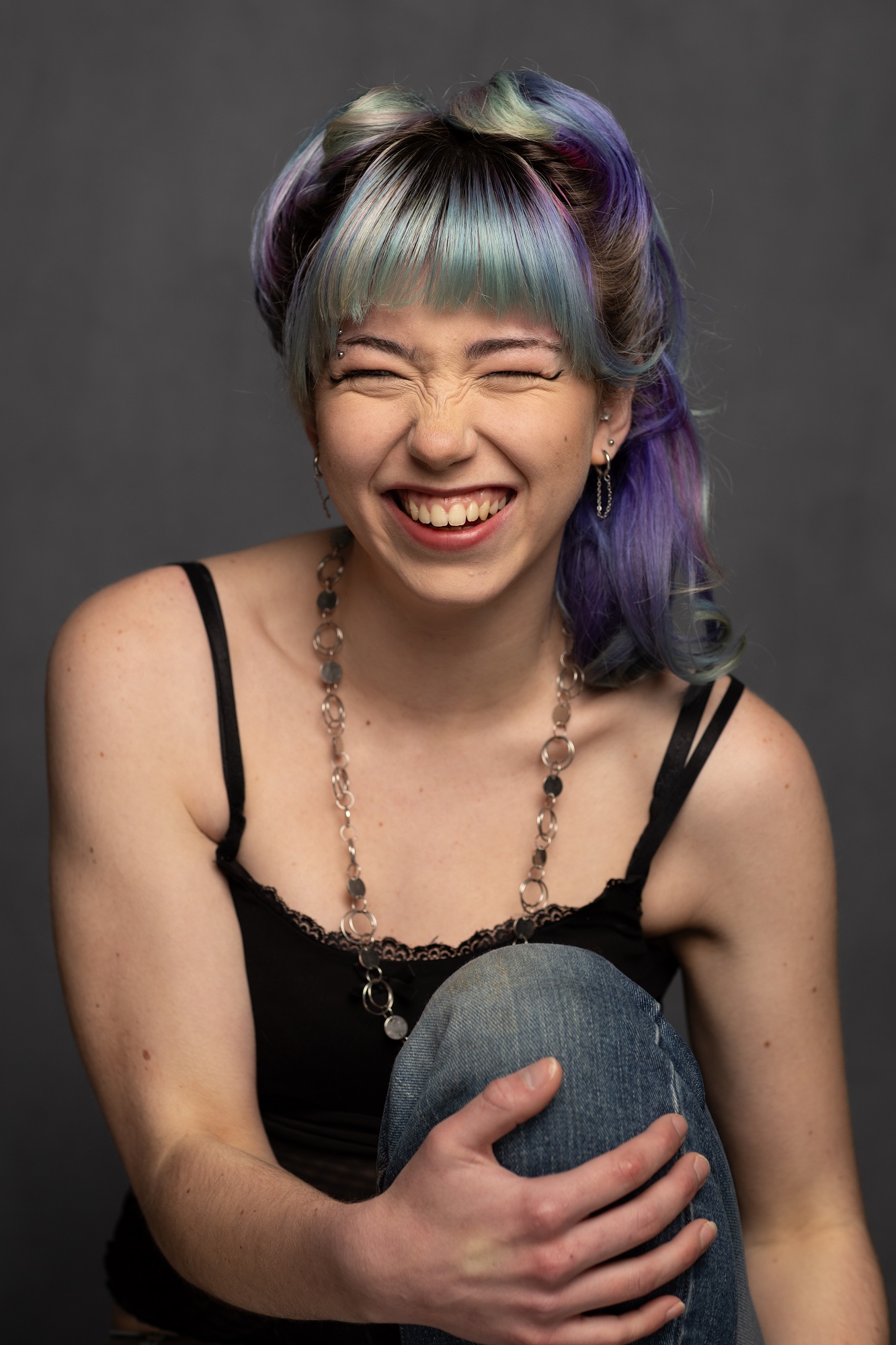 Model with colourful hair holding her knee - she is laughing