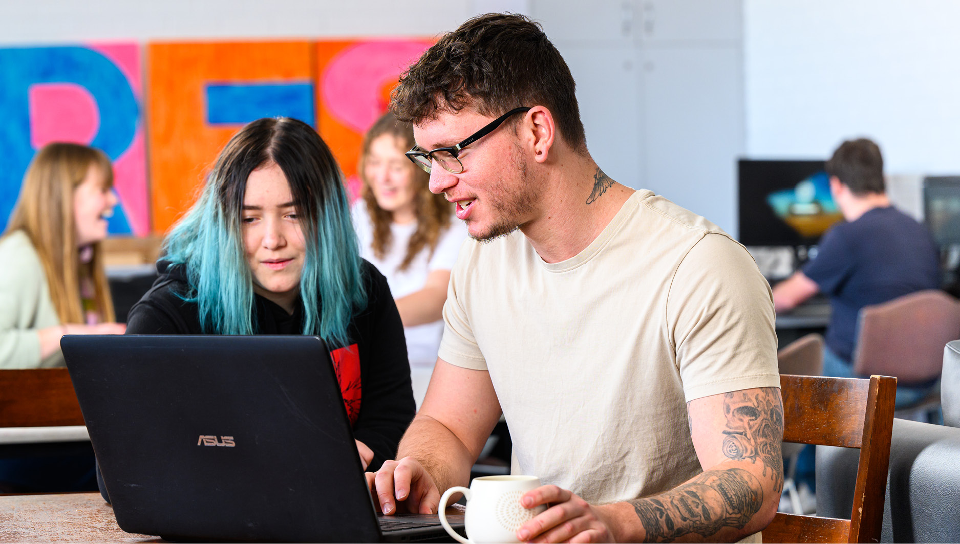 Image of 2 students working with a laptop at a table